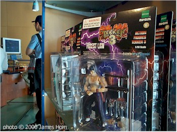 Tekken action figure "Forest Law", a Bruce Lee-lookalike, looks on as gamers try out the PS2